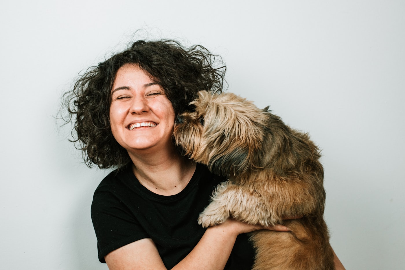 A happy Australian owner being nuzzled by her dog at home